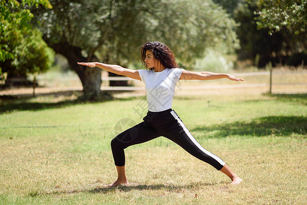 轻的阿拉伯女人大自然中瑜伽北非女穿着运动服,城市公园战士II的身影图片