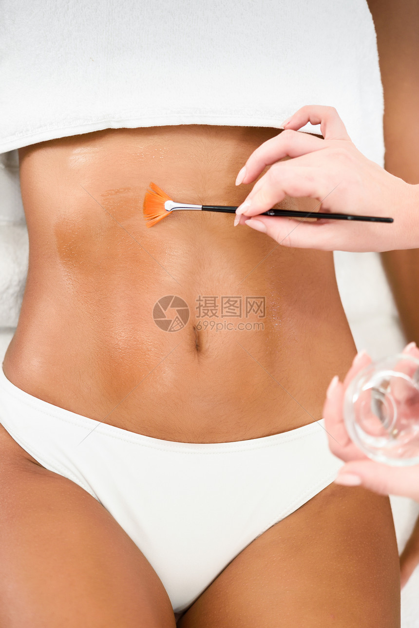 水疗保健中心接受油刷腹部按摩治疗的妇女美美学图片