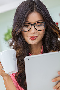 美丽的亚洲中国妇女戴着眼镜,用平板电脑咖啡店电脑喝咖啡茶图片