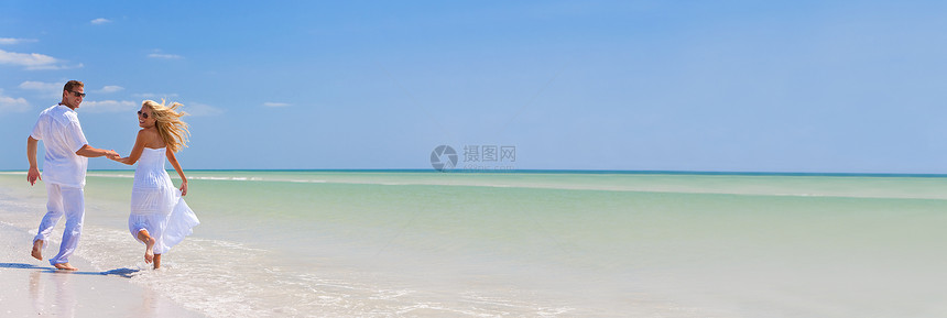 全景横幅快乐的轻男女夫妇奔跑,欢笑牵手个荒凉的热带海滩上,明亮的蓝天图片