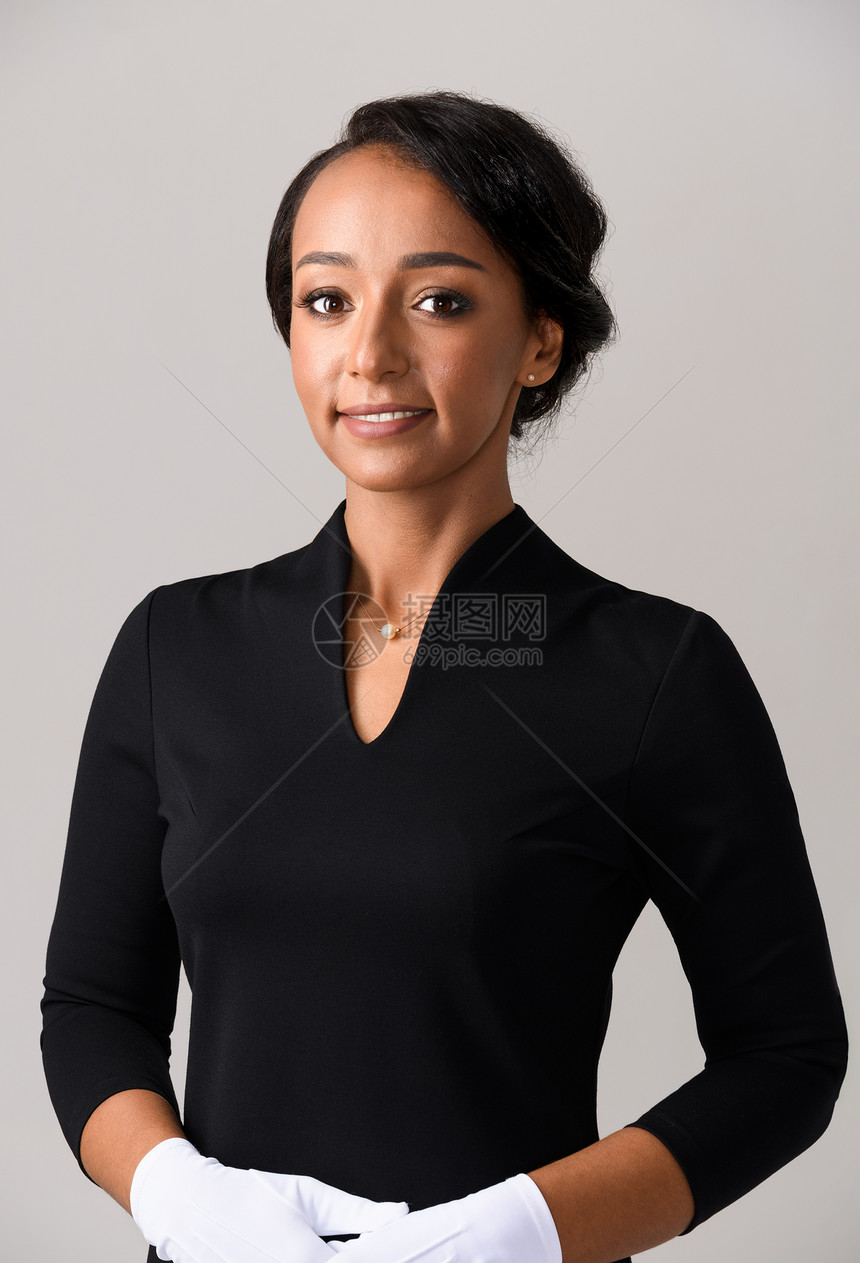 空姐穿着黑色衣服白色手套灰色背景上微笑的非洲女空姐空姐肖像图片