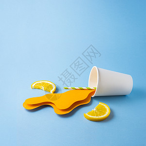 创意照片带走杯子与飞溅橙汁制成的纸蓝色背景图片