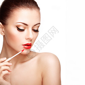 发油美丽的轻女人用口红涂嘴唇完美的化妆美容时尚完美的皮肤背景
