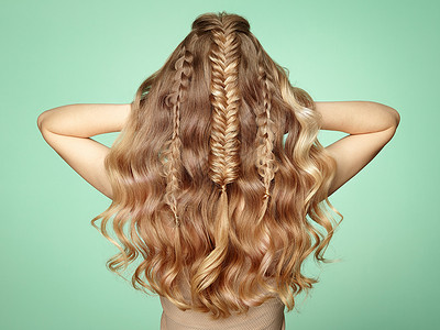 头又长又亮的卷发的金发女孩漂亮的模特,留着卷曲的发型护理美容美发产品辫子的女士背景图片