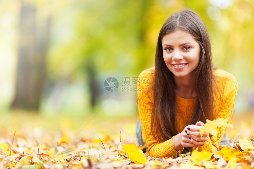 位美丽的黑发女人躺秋天的公园里的肖像图片
