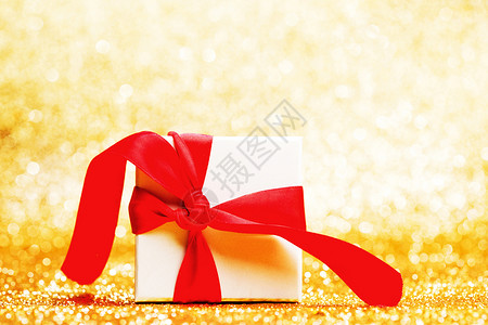 白色礼品盒,红色丝带金色闪光的背景上图片