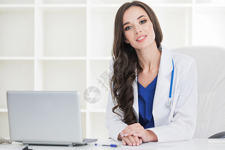 医疗后台管理系统女医生办公桌上工作,镜头前微笑,后台的办公室内部女医生办公桌上工作背景