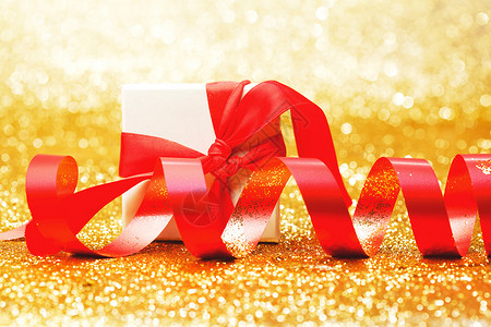 白色礼品盒,红色丝带蝴蝶结金色闪光的背景上图片