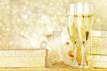 两个优雅的长笛闪闪发光的香槟与装饰金色的礼物图片