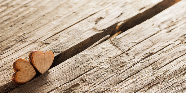 两颗小木心旧的开裂的木头背景上两颗木头心图片