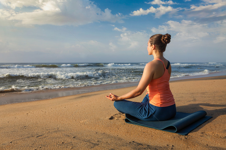 妇女瑜伽冥想放松帕德马萨纳莲花姿势户外热带海滩日落海滩上瑜伽莲花姿势的女人图片