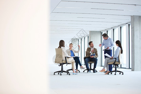 成熟的商人与新办公室坐椅子上的队讨论图片