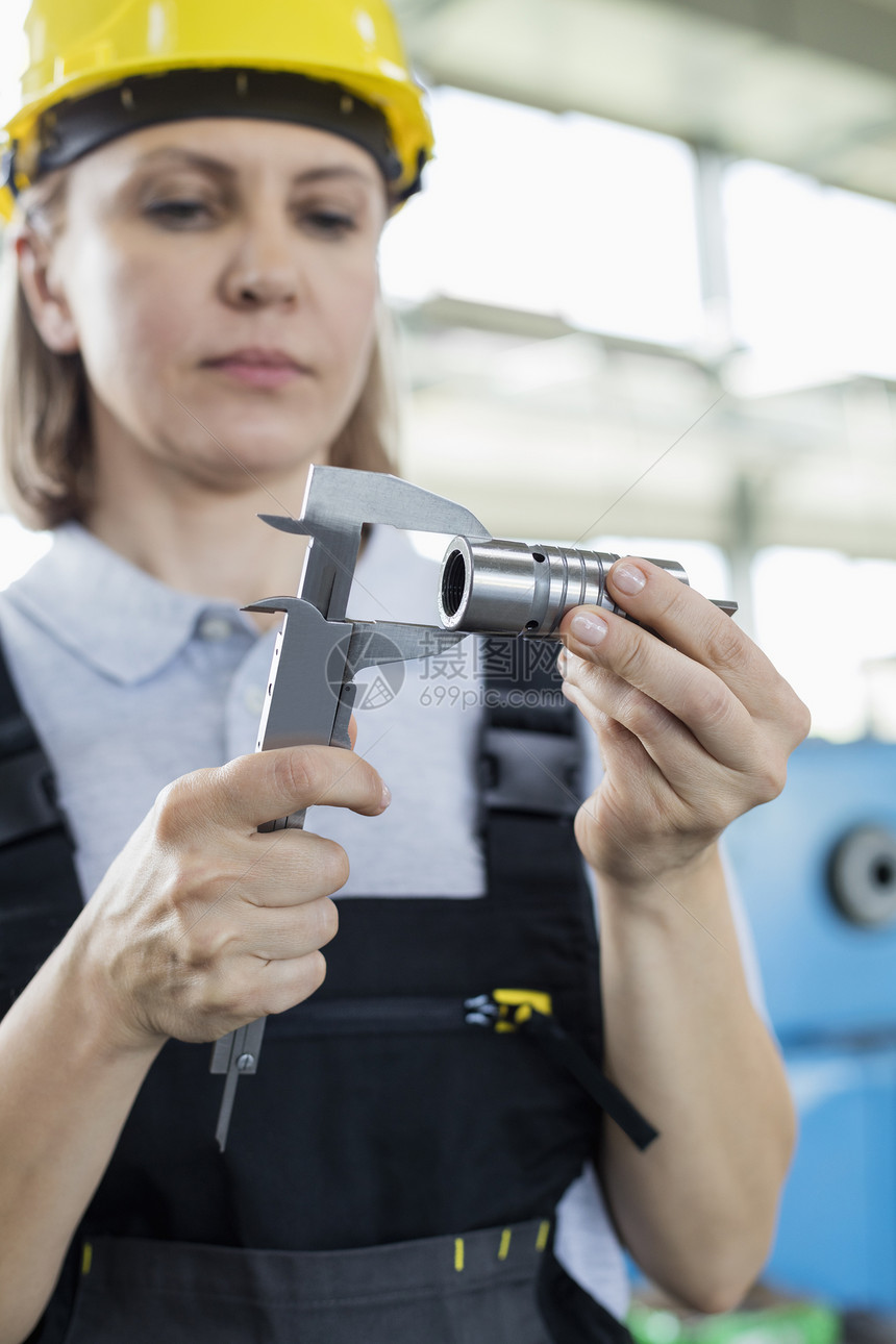 工厂成熟的女职工用卡尺测量金属图片