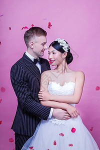 优雅的新婚夫妇拥抱,同时站粉红色的背景图片