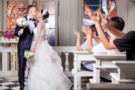 新婚夫妇教堂接吻时,婚礼客人鼓掌高清图片