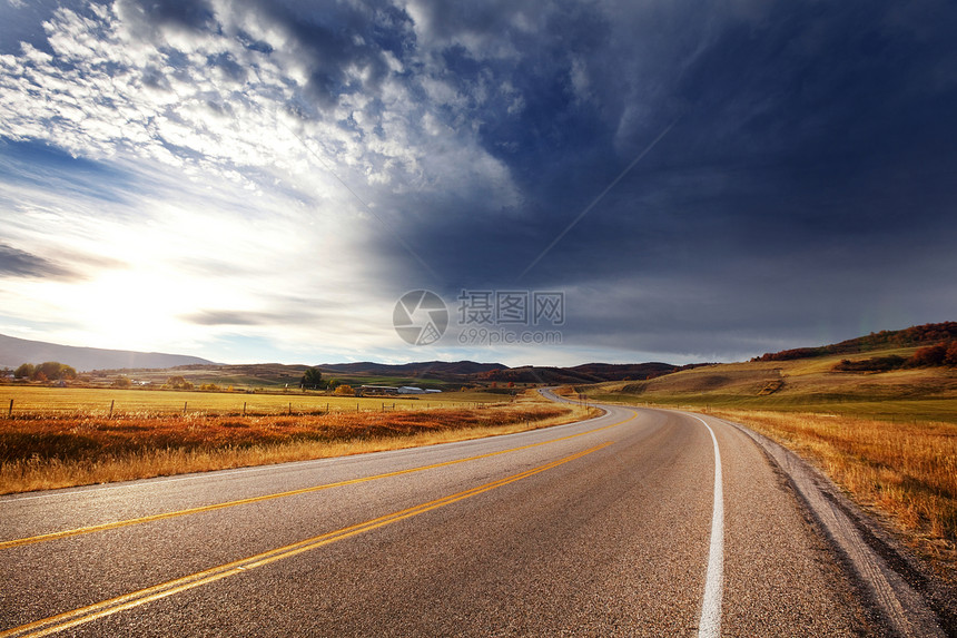 阳光明媚的早晨,乡间道路上五彩缤纷的秋天景象图片