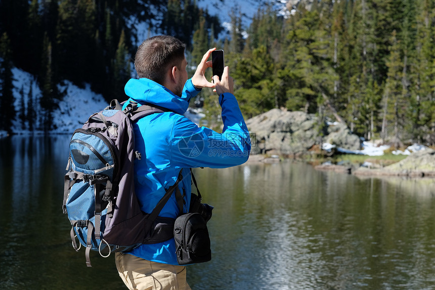 徒步旅行者与背包拍照与智能手机附近熊湖秋天的洛基山公园科罗拉多,美国图片