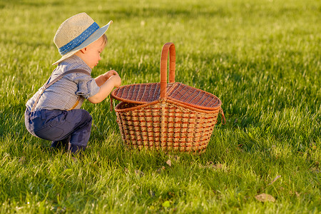 户外幼儿的肖像农村场景,岁的小男孩戴着草帽,看着野餐篮图片