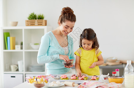 家庭,烹饪人们的快乐的母亲小女儿家庭厨房用巧克力洒来制作装饰纸杯蛋糕快乐的母亲女儿家纸杯蛋糕背景图片