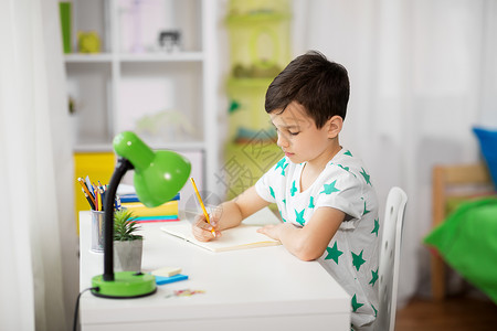 教育,童学校的小男孩坐桌子上,家里写笔记本小男孩家给笔记本写信图片