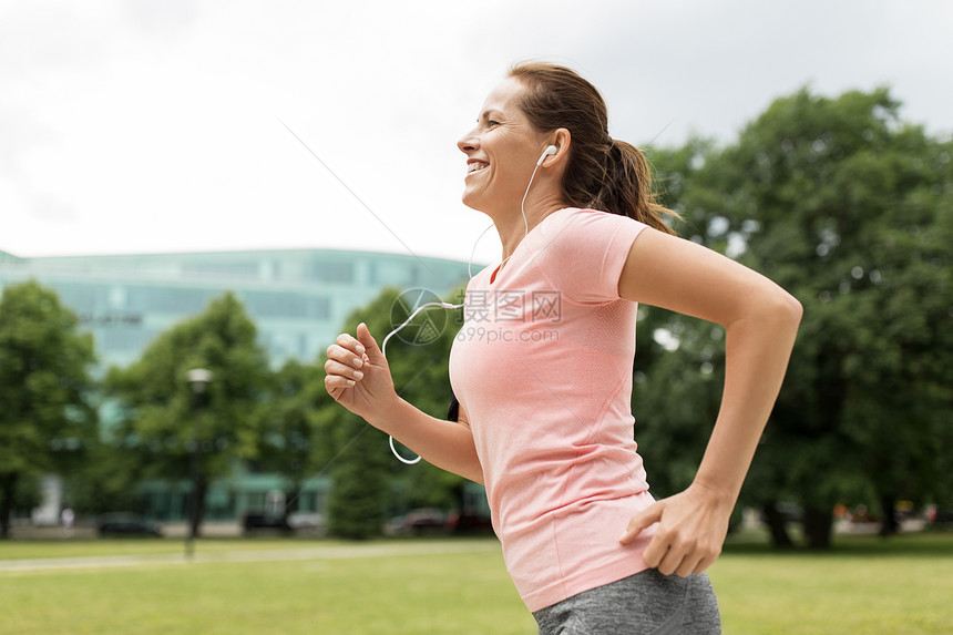 健身,运动健康的生活方式微笑的女人带着耳机公园跑步听音乐耳机的女人公园跑图片