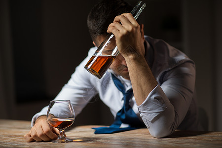 酒精中,酒精成瘾人的男酒精与瓶子喝白兰地桌子上晚上醉汉晚上桌子上喝酒背景图片