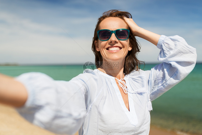 暑假休闲快乐的微笑女人戴着太阳镜海滩上自拍戴太阳镜的女人夏天的海滩上自拍图片