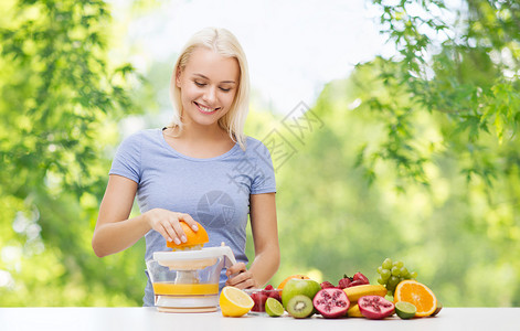 健康的饮食,食物,饮食排微笑的女人与挤压机制作果汁橙色新鲜的绿色自然背景快乐的女人果汁橘子新鲜背景图片