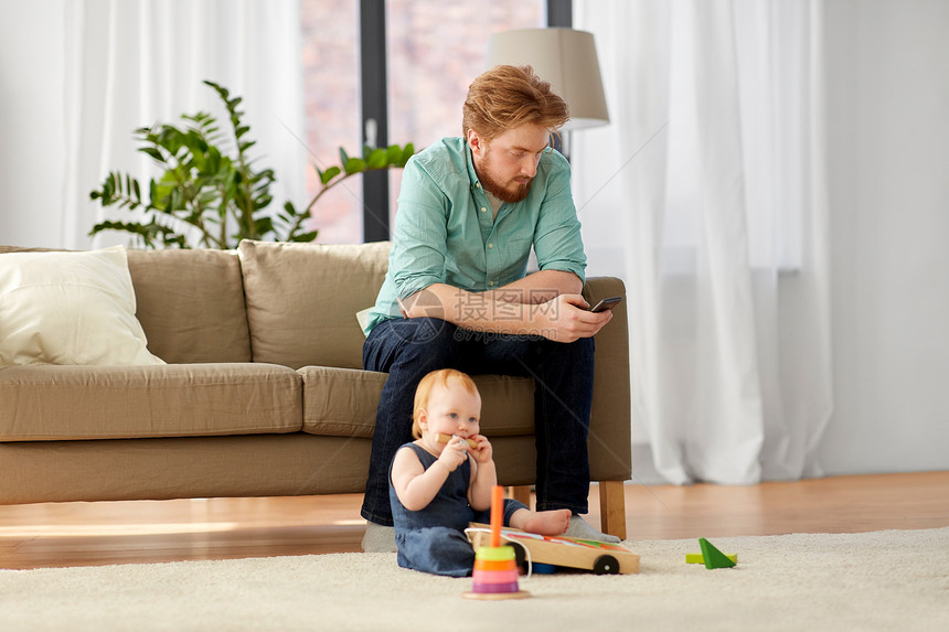 家庭,父亲技术红头发的父亲与智能手机小女儿玩玩具积木套件家里父亲带着智能手机婴儿家玩图片