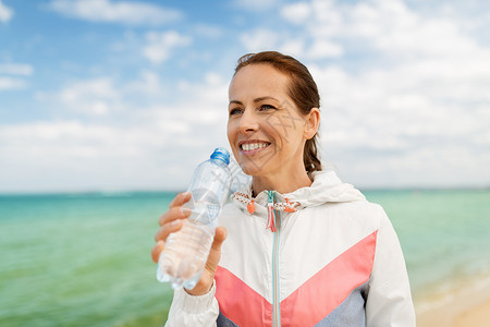 健身,运动健康的生活方式妇女海滩锻炼后饮水女人海滩上锻炼后喝水图片