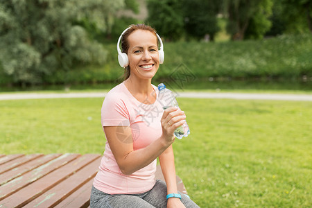 健身,运动健康的生活方式女耳机饮用水后,公园锻炼女人戴着耳机公园喝水图片