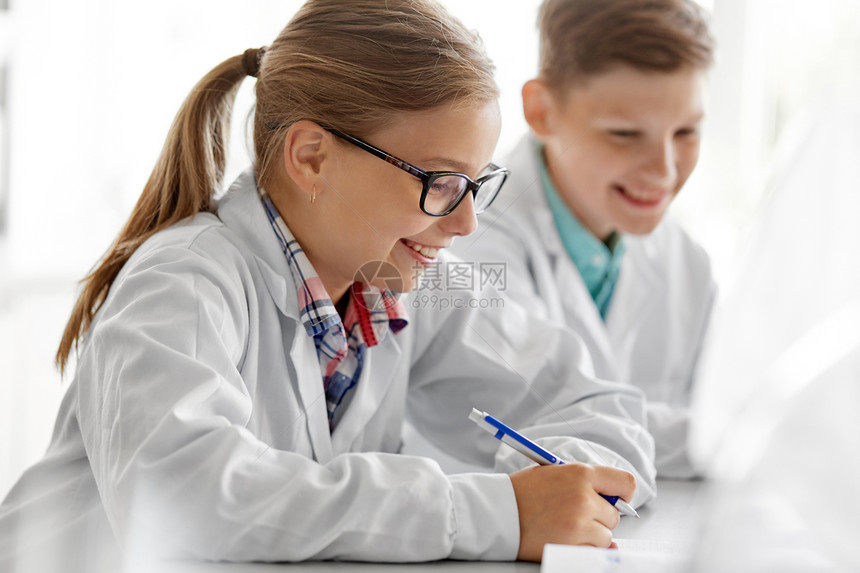 教育科学儿童学校实验室学化学的快乐女孩的特写,并写信给工作簿快乐的女孩学校实验室学化学图片