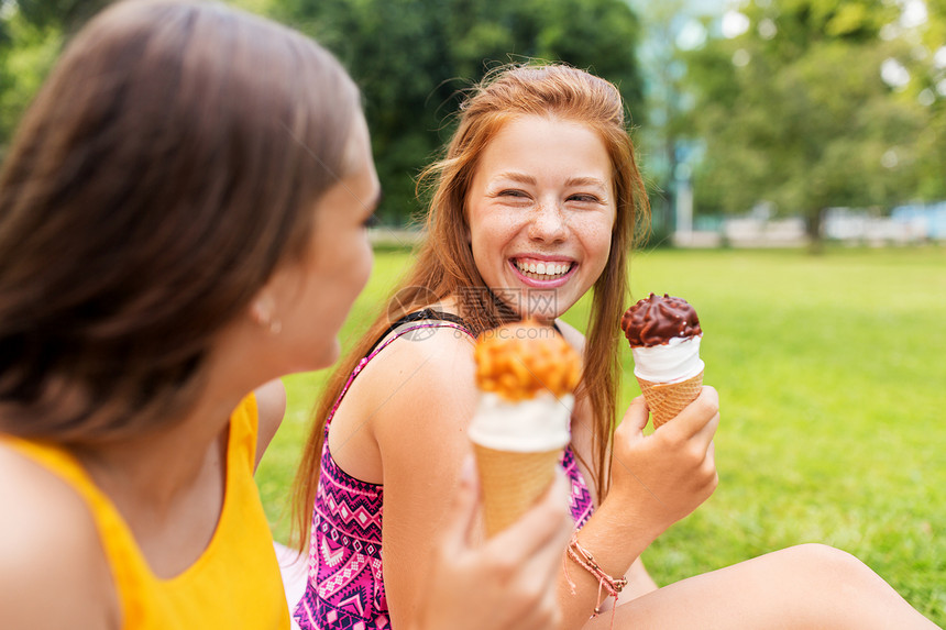 休闲友谊的快乐微笑的十几岁女孩朋友夏季公园野餐时吃冰淇淋十几岁的女孩公园野餐时吃冰淇淋图片