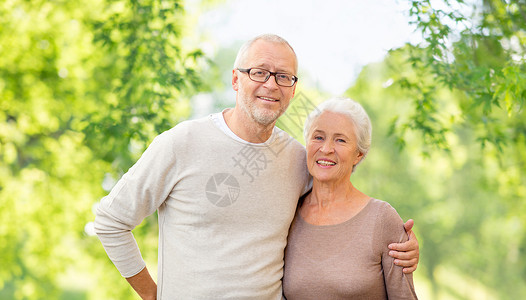 老人的幸福的老夫妇拥抱绿色的自然背景老夫妇拥抱自然背景图片