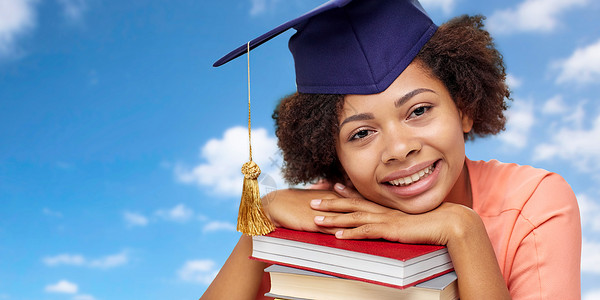 教育,学校,知识毕业快乐微笑的非裔美国研究生女孩灰泥板与书籍梦想蓝天背景用书非洲研究生背景图片