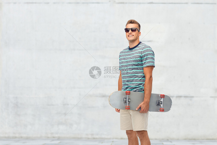 运动,休闲滑板微笑的轻人与滑板混凝土墙壁背景微笑的轻人,滑板超过白色图片