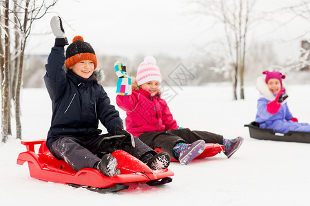 童,雪橇季节的群快乐的孩子冬天滑着雪橇,挥舞着手快乐的小孩子冬天滑雪橇图片