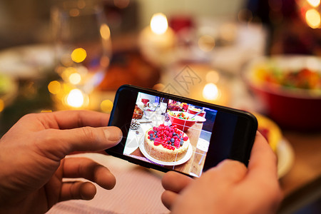 食物技术假日诞节晚餐时,用智能手机近距离拍摄蛋糕诞节晚餐时双手拍照食物图片