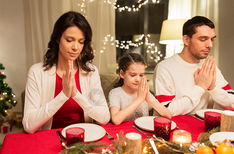 节日,家庭感恩的快乐的母亲,父亲小女儿吃诞晚餐,并家里吃饭前祈祷家人诞晚餐前祈祷背景图片
