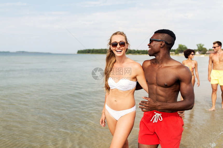 友谊,暑假关系的快乐的混合种族夫妇步行沿海滩与朋友混合种族夫妇朋友沿着海滩散步图片