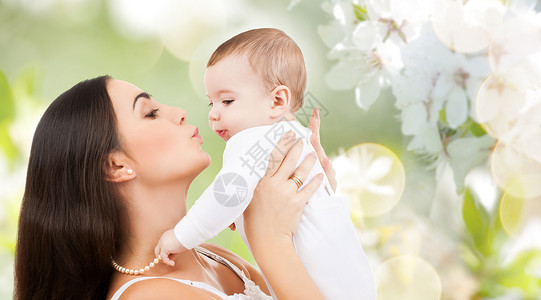 家庭母亲的快乐的微笑轻母亲亲吻小婴儿樱花背景母亲樱花背景下亲吻婴儿图片