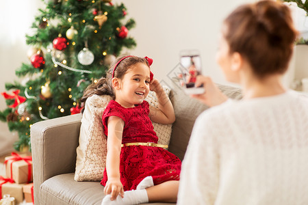 诞节,技术家庭母亲家里用智能手机拍摄小女儿母亲诞节电话想象女儿图片