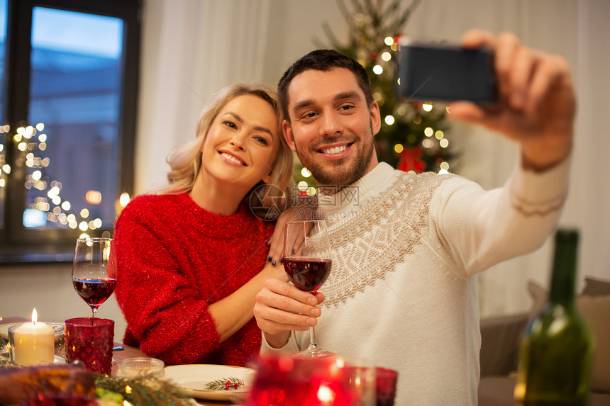 诞节,假日,技术人的快乐的夫妇家里吃晚饭时用智能手机自拍快乐的夫妇诞晚餐上自拍图片
