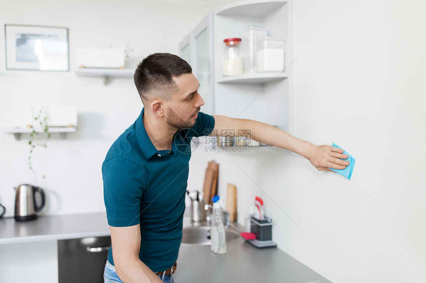 家庭人的男人家里厨房用布清洁墙壁家里厨房里抹布清洁墙的男人图片
