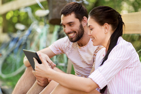 人,技术生活方式的快乐的夫妇与平板电脑电脑自行车夏季公园与平板电脑自行车夏季公园背景图片