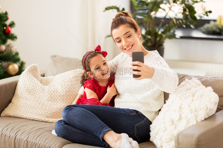 诞节,技术家庭快乐的母亲小女儿家里用智能手机自拍家人家用智能手机自拍图片