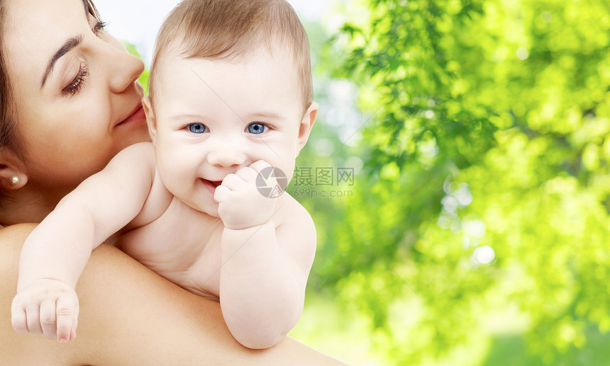 家庭母亲的快乐的微笑轻母亲与小婴儿超过绿色的自然背景母亲带着孩子绿色的自然背景下图片