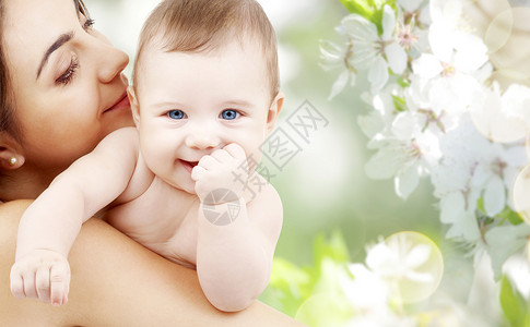 家庭母亲的快乐微笑的轻母亲与小婴儿樱花背景把妈妈孩子关樱花上图片