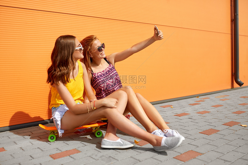 友谊,休闲技术快乐的十几岁女孩朋友与短滑板自拍智能手机城市街道夏天十几岁的女孩带着滑板自拍图片