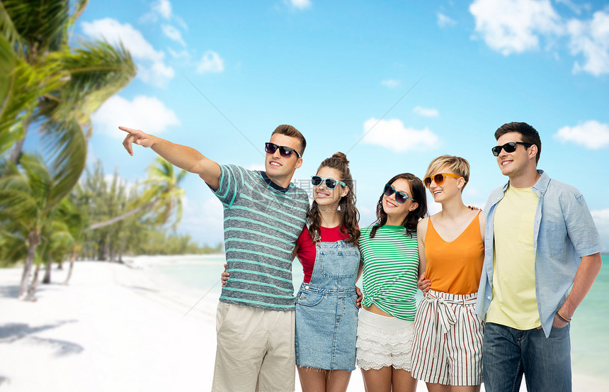 友谊,旅游,旅游暑假的群快乐的微笑的朋友,戴着太阳镜,拥抱着,指着法属波利尼西亚热带海滩背景上的东西异国情调的海图片